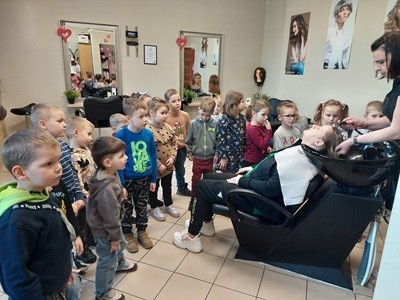 grupa dzieci z przedszkola z wizyta w salonie fryzjerskim