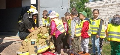 dzieci oglądają umundurowanie pokazywane przez strażaka 