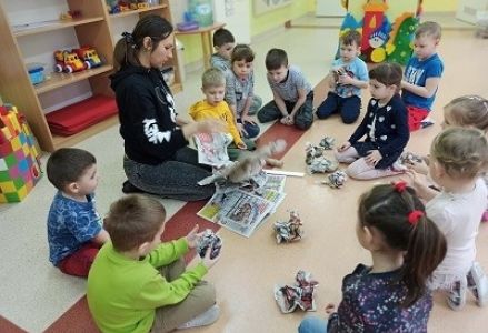 dzieci siedzą na podłodze i zgniatają gazetę