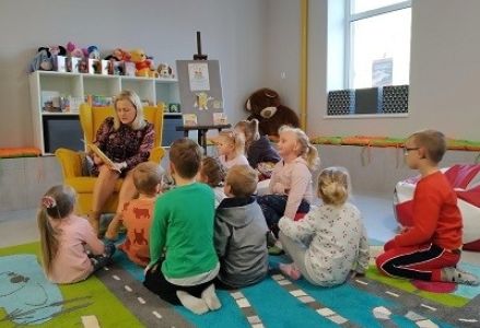 dzieci oglądają ksiażkę trzymaną przez bibliotekarkę