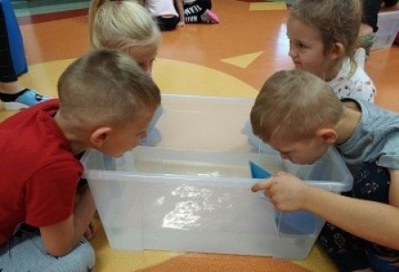 dzieci dmuchają na papierowe łódki