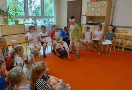grupa dzieci przedszkolnych podczas wizyty uczniów klasy pierwszej w przedszkolu
