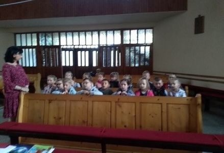 dzieci siedzą w ławce w kościele