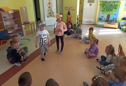 Dzieci w kole dwója z nich ma opaski z ziemią i słońcem