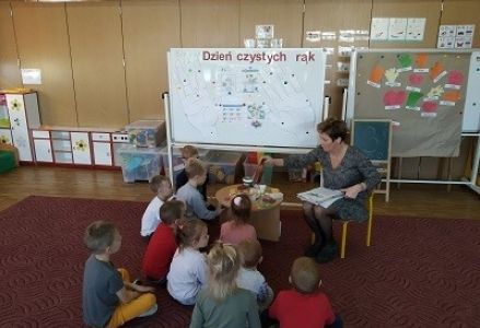 dzieci siedzą przed stoliczkiem z mydłami