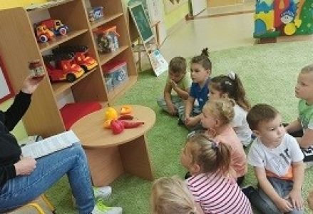 dzieci siedzą przed pielęgniarką, która pokazuje im różne papryki