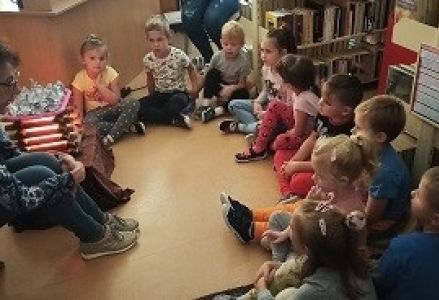 dzieci siedzą na przeciwko bibliotekarki