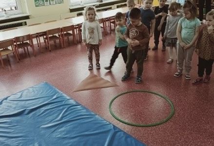 dzieci stoją przed figurami koła i trójkąta