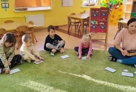 dzieci siedzą na dywanie z kopertami
