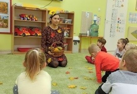 dzieci siedzą w kol z panią jesienia