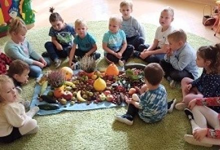 dzieci siedzą wokoło darów jesieni