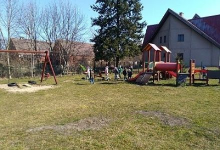 dzieci stoją z marzanną przed przedszkolem