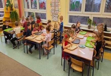 Dzieci z grupy przedszkolnej tworzą ozdoby choinowe i wieszają je na przedszkolnej choince