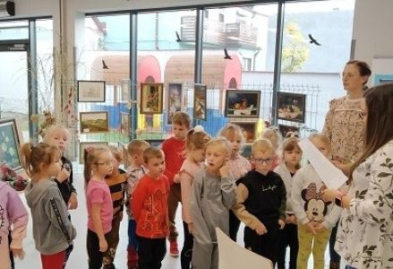 dzieci słuchają informacji odczytywanej przez bibliotekarkę