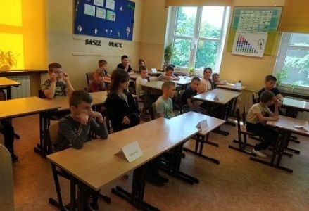 dzieci siedzę w szkolnych ławkach