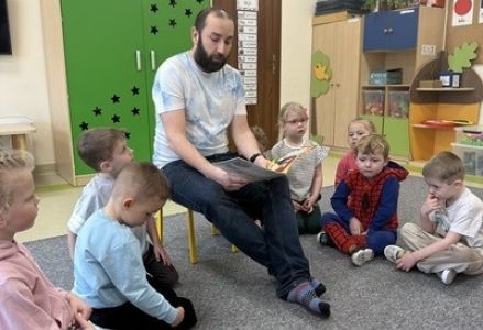 grupa dzieci przedszkolnych podczas wizyty rodzica czytającego bajki w ramach akcji "Cała Polska Czyta Dzieciom"