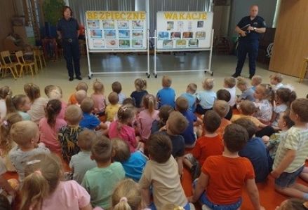 grupa dzieci przedszkolnych podczas spotkanie ze strażą miejską pt.: "Bezpieczne wakacje"