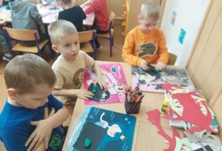 grupa dzieci podczas zajeć  plastycznych lepi dinozaury z plasteliny