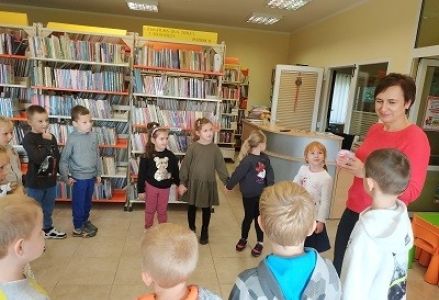 dzieci stoją w kole z bibliotekarką