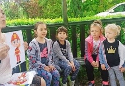 dzieci siedzą pod wiatą z panią logopedą