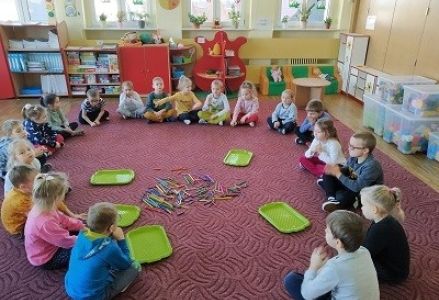 dzieci siedzą przed rozłożonymi kredkami