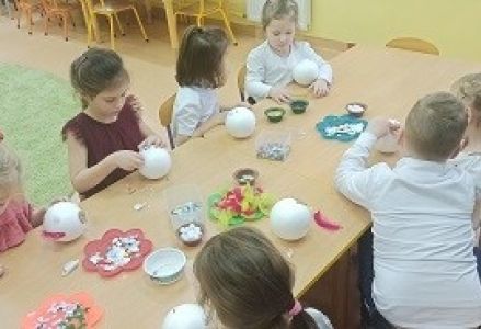 dzieci siedzą przy stoliczku z kreatywnymi ozdobami
