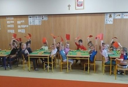 dzieci trzymają w górze czerwone kartki