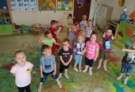 dzieci stoją na foli malarskiej i się uśmiechają