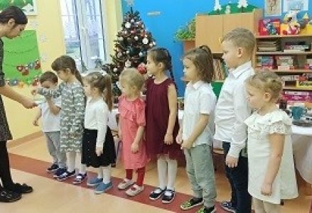 dzieci stoją w rzędzie przed wychowawcą