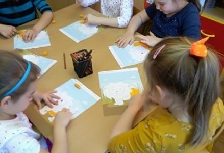 dzieci siedzą przy stoliku i wyklejają kontur plasteliną