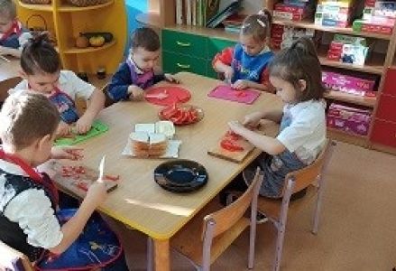 dzieci przy stoliczkach przygotowują kanapki