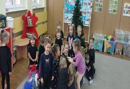Dzieci z grupy przedszkolnej wieszają ozdoby na choinkę