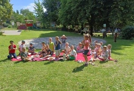grupa dzieci przedszkolnych podczas pikniku na przedszkolnym placu zabaw