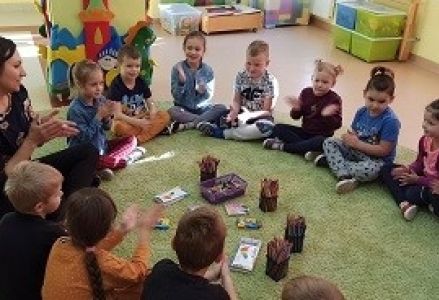 dzieci z nauczycielką siedzą w kole