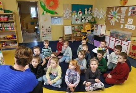dzieci siedzą na dywanie przed panią pielęgniarką